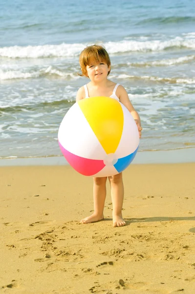 Happy toddler girl playing with her colorful ball at beach — Stock Photo, Image