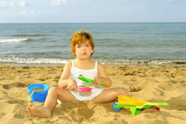 Menina criança feliz brincando com seus brinquedos na praia — Fotografia de Stock