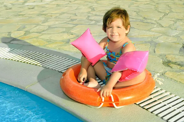 Niña feliz sentada junto a la piscina — Foto de Stock