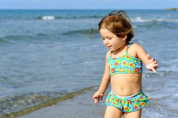 Gelukkig peuter meisje uitgevoerd op strand — Stockfoto