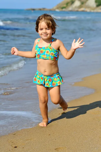 Gelukkig peuter meisje uitgevoerd op strand — Stockfoto