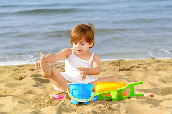 Happy toddler girl playing with her toys at beach — Stock Photo, Image