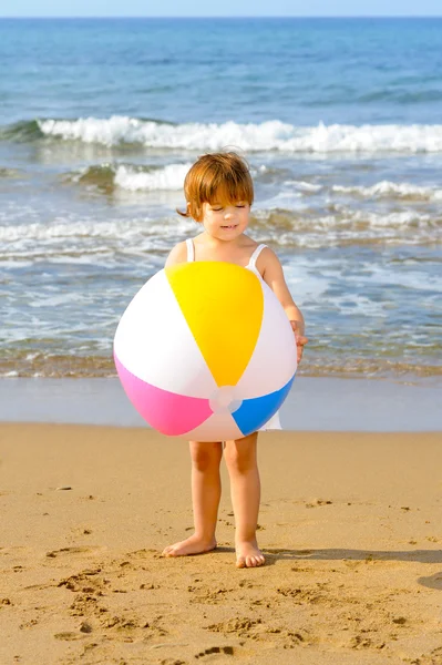 Happy toddler girl playing with her colorful ball at beach — Stock Photo, Image