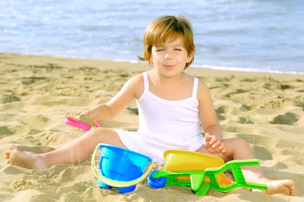 Feliz niña jugando con sus juguetes en la playa —  Fotos de Stock