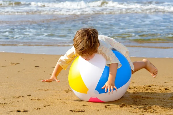 Fröhliche Kleinkind Mädchen spielt mit ihrem bunten Ball am Strand — Stockfoto