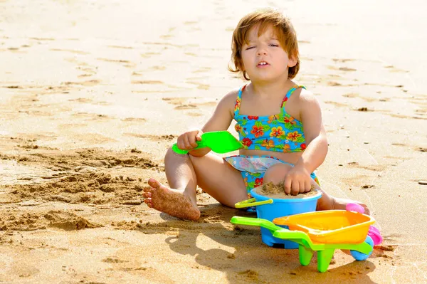 Happy toddler girl playing with her toys at beach — Stock Photo, Image