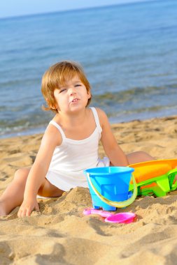 Kumsalda onun oyuncakları ile oynarken mutlu bebek kız