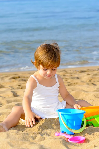 Kumsalda onun oyuncakları ile oynarken mutlu bebek kız