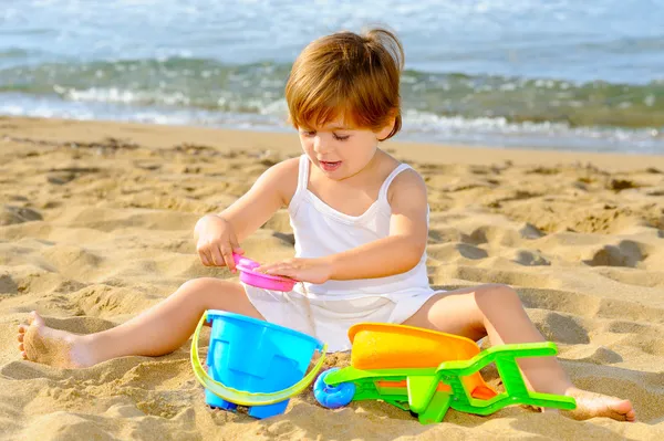 Glada barnet Tjej leker med hennes leksaker på stranden — Stockfoto