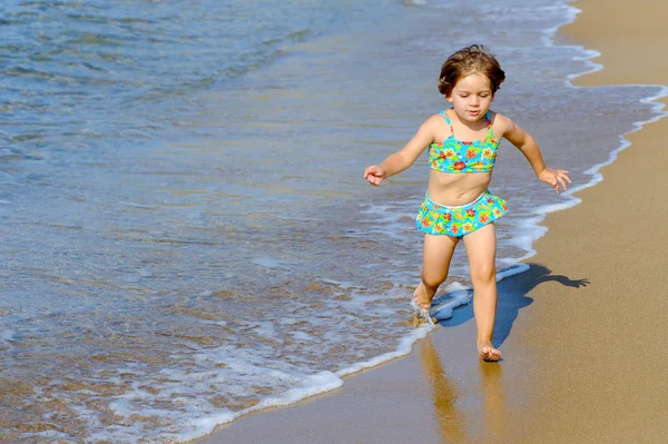 Gelukkig peuter meisje uitgevoerd op strand — Stockfoto