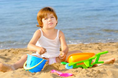 Kumsalda onun oyuncakları ile oynarken mutlu bebek kız