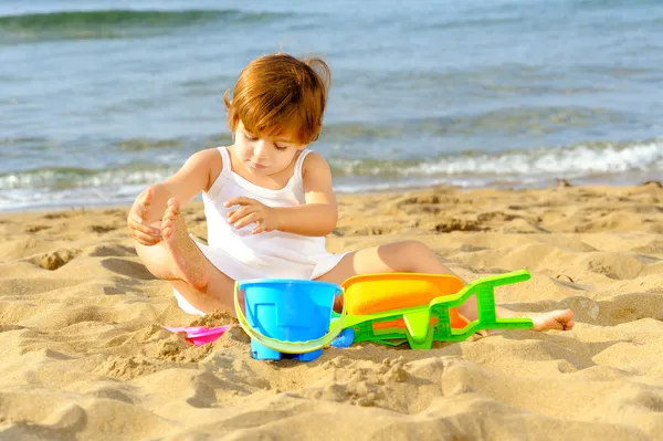 Happy toddler girl playing with her toys on the beach — Stock Photo, Image