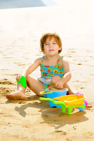 Happy toddler girl playing with her toys on the beach — Stock Photo, Image