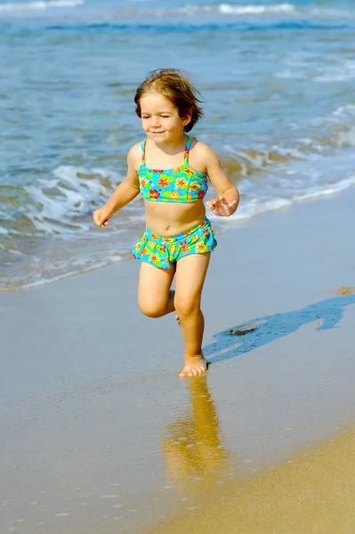Glada barnet flicka kör på stranden — Stockfoto