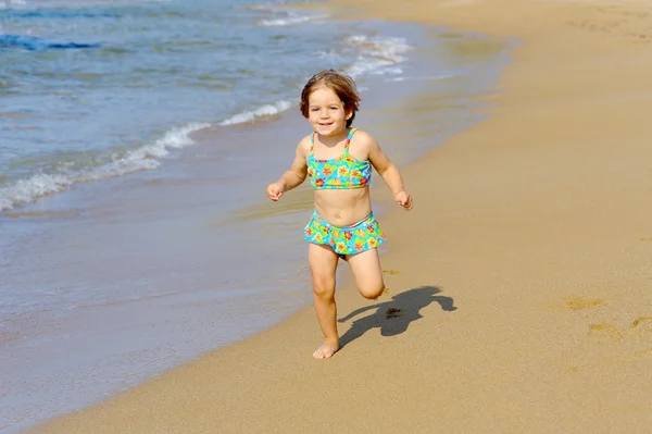 快乐蹒跚学步女孩在海滩上运行 — 图库照片