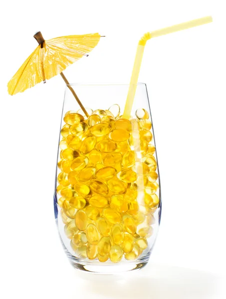 Gezonde Vitamine cocktail: gele olie pillen in transparant glas — Stockfoto
