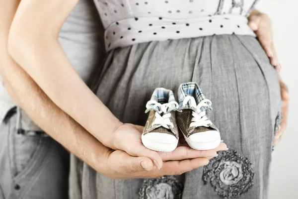 Newborn baby booties in parents hands. Close up. — Stock Photo, Image