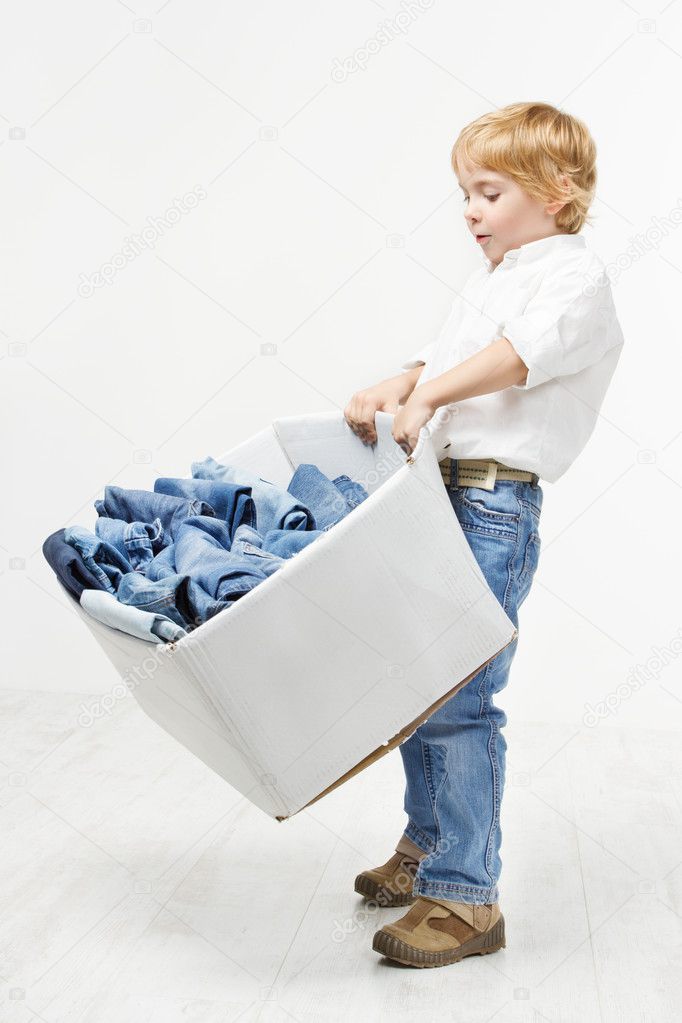 Child carrying cardboard box packed with jeans. Kids clothing fa