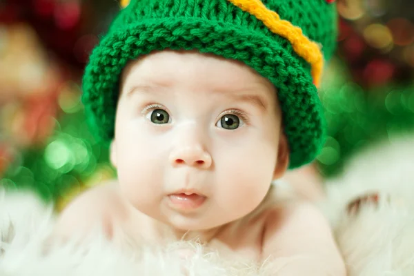 Gyönyörű baba kötés zöld kalapban — Stock Fotó