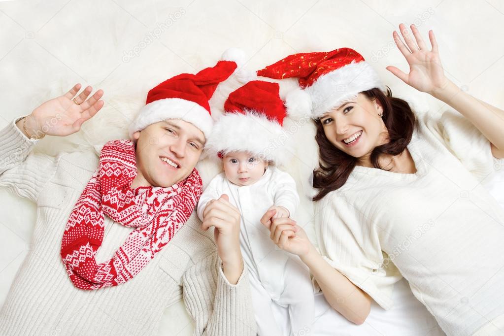 Christmas family of three persons in red hats. Hapy parents