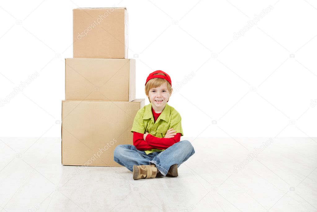 Boy sitting in front of carton boxes pyramid.