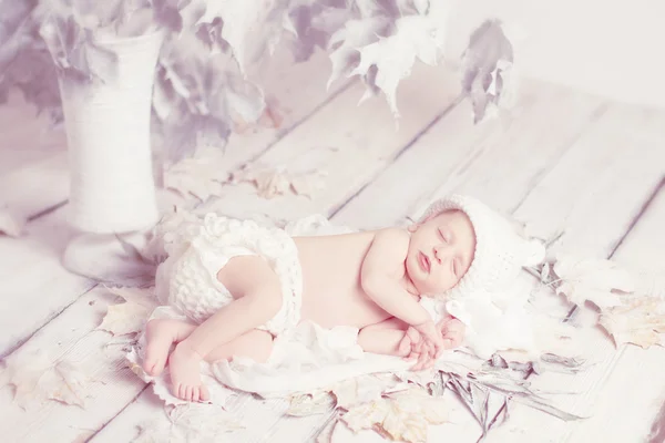 Bebê recém-nascido dormindo em folhas sobre fundo de madeira branca. Fios — Fotografia de Stock