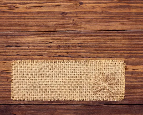 Etiqueta de pano de saco sobre fundo placa de madeira marrom — Fotografia de Stock