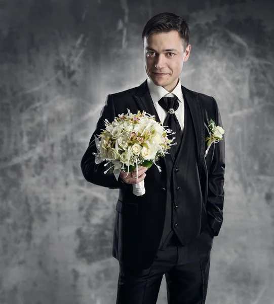 Man in black suit with flowers bouquet. Wedding groom fashion. G