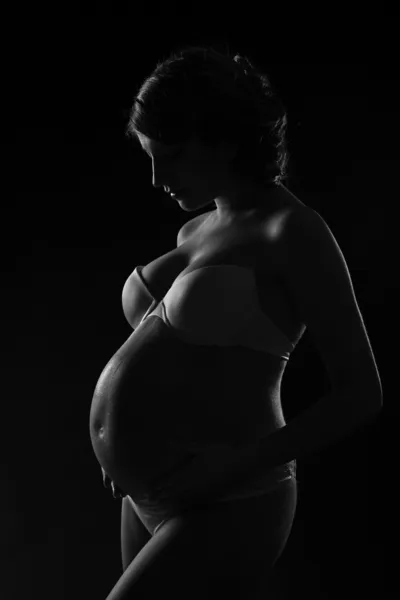 Mujer embarazada silueta sobre fondo negro . — Foto de Stock
