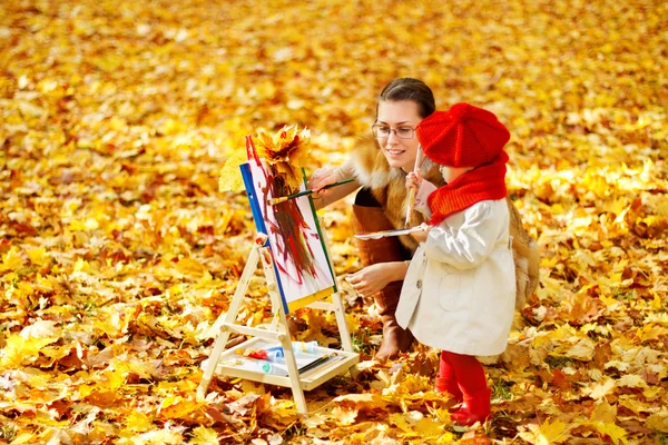 Μητέρα και παιδί σχέδιο για καβαλέτο σε κίτρινο πάρκο φθινόπωρο. δημιουργική παιδιά — Φωτογραφία Αρχείου