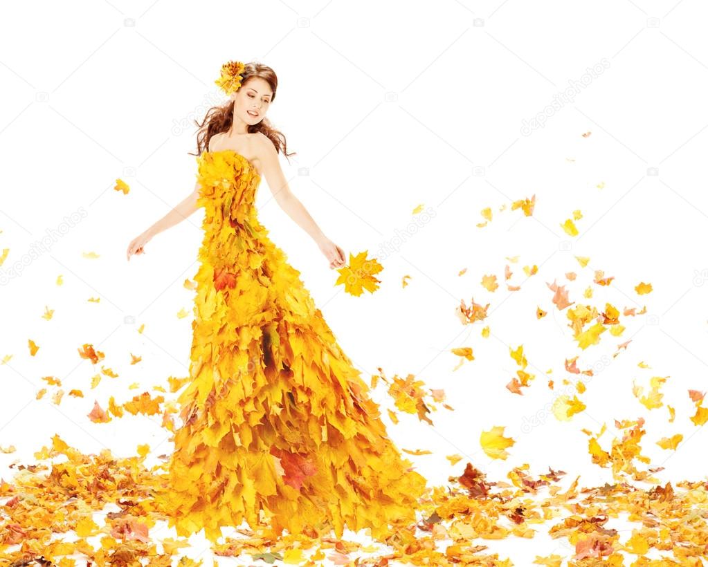 Autumn woman in fashion dress of maple leaves holding leaf