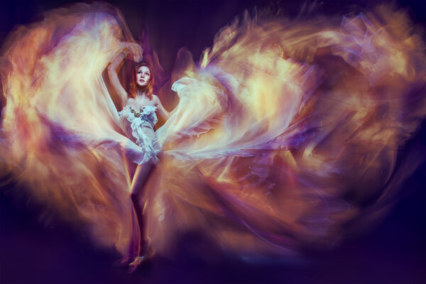 Женщина в махающем платье в виде пламени танцует с летающей тканью. Дар
