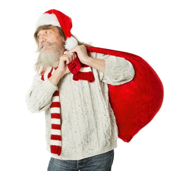 Christmas old man with beard in red hat carrying Santa Claus bag — Stock Photo, Image
