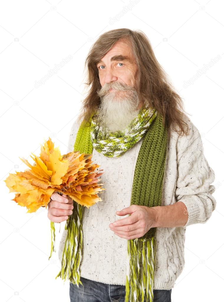 Senior old man, beard and long hairs, holding autumh yellow maple leaves
