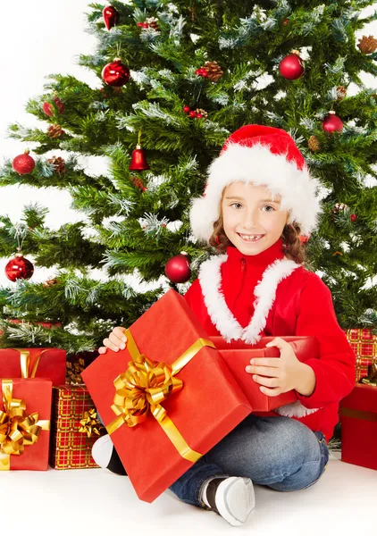 Christmas child open gift box, sitting under fir tree Royalty Free Stock Images