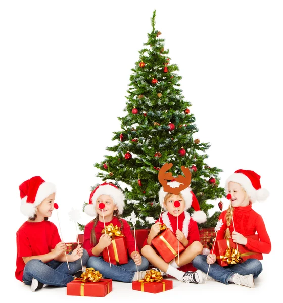 Ayudantes de Navidad niños en Santa sombrero jugando bajo el abeto sobre fondo blanco — Foto de Stock