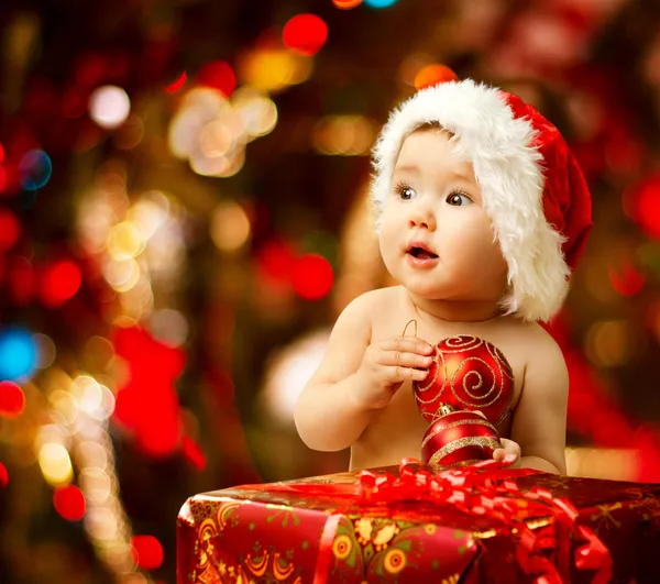 Bebé de Navidad en sombrero de santa cerca de la caja de regalo regalo rojo —  Fotos de Stock