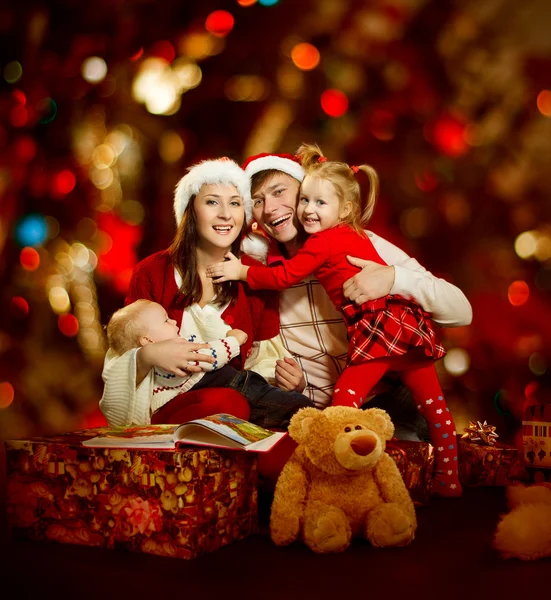 Weihnachtliche vierköpfige Familie lächelt glücklich über roten Hintergrund — Stockfoto