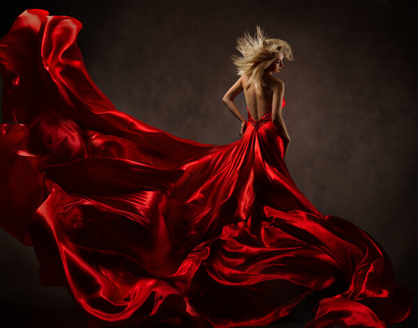 Woman in red waving dress with flying fabric. Back side vie