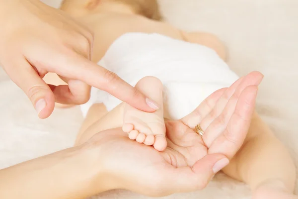 Massagetherapeut pasgeboren baby voet in moeder hand — Stockfoto