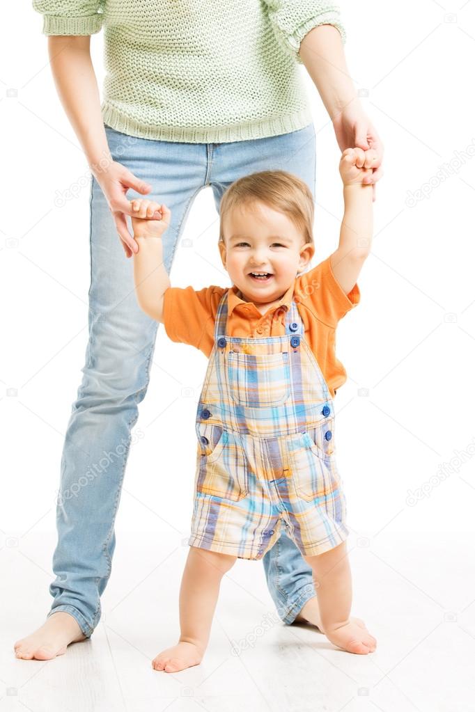 Baby happy go first steps. Mother helping child stand, white background