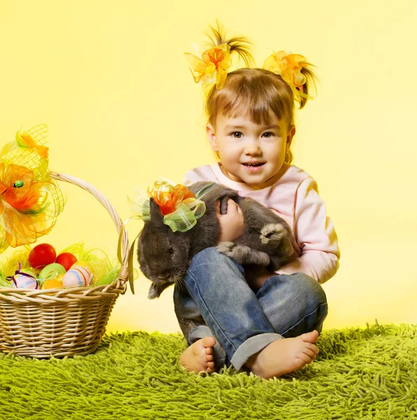 Easter little girl, kid holding bunny rabbit basket eggs over yellow background — Stock Photo, Image