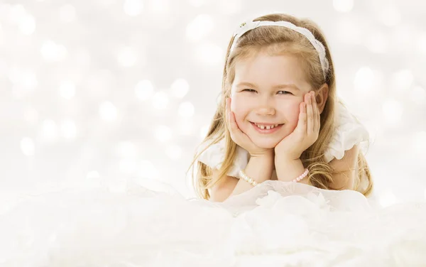 Liten tjej glad leende, liggande händer under kinder. vit bakgrund — Stockfoto