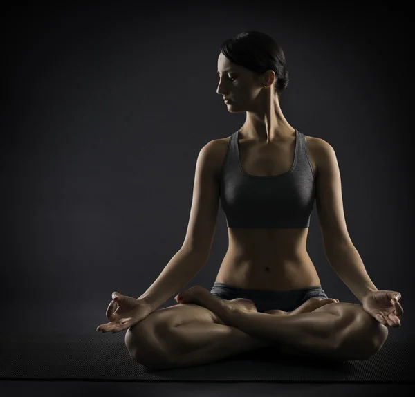 Femme de yoga méditer assis dans la pose de lotus. Silhouette de fille d'exercice sur fond noir — Photo