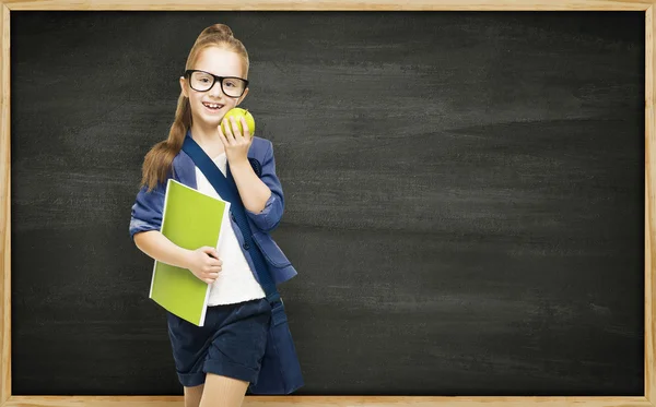Schoolgirl with book apple and blackboard, school girl child on black board background, elementary education concept — Stock Photo, Image