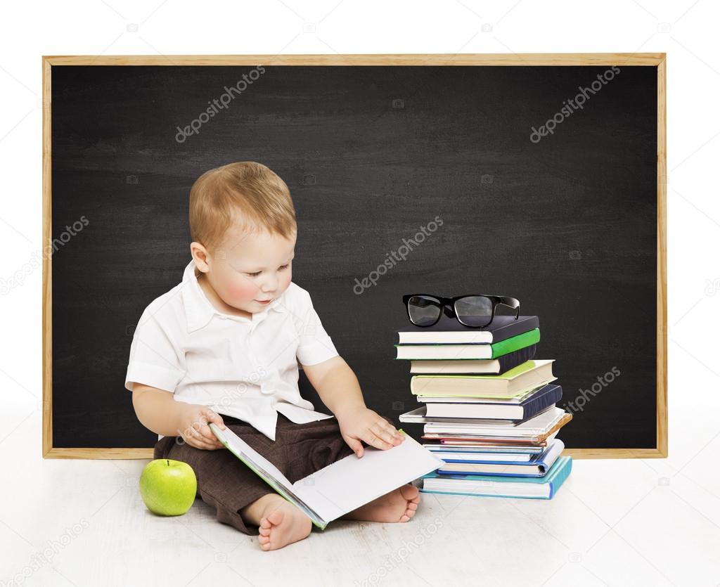 Schoolboy reading book near blackboard, kindergarten school boy, little child on black board background, elementary education concept