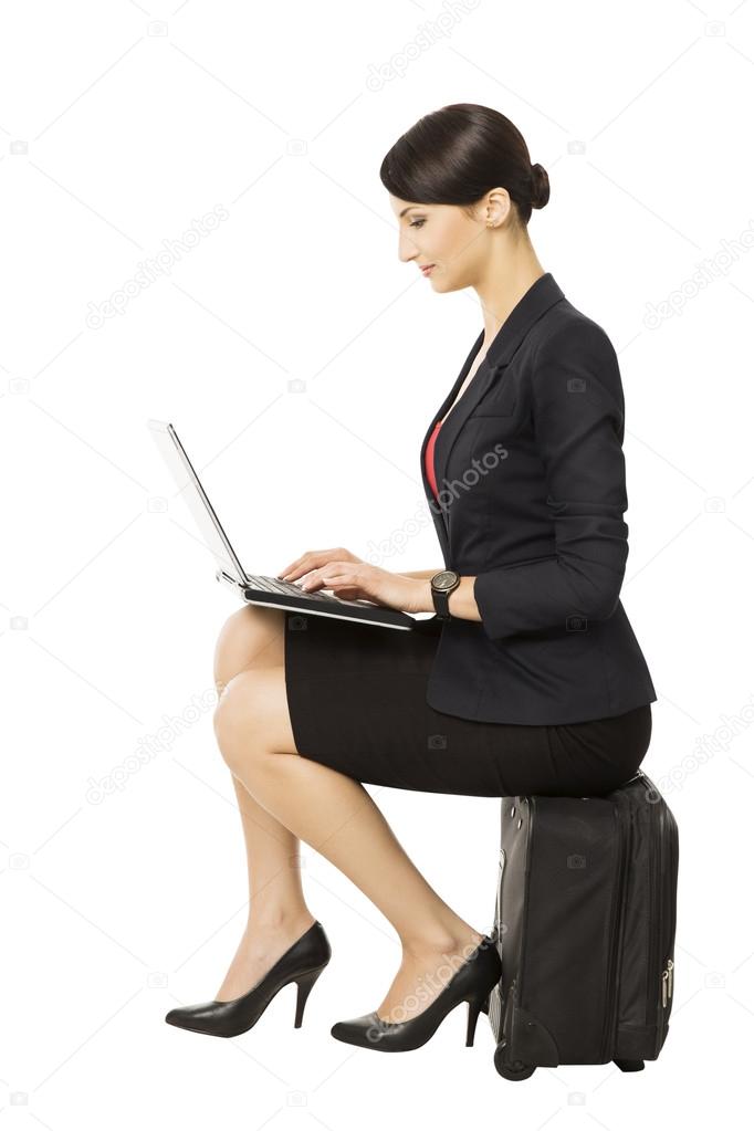 Business woman looking at notebook sitting on suitcase, isolated over white background, manager or employee mobility, businesswoman in business trip