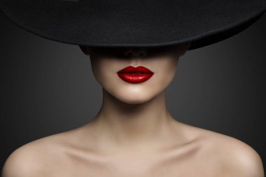 Red Lips Make up Closeup. Mysterious Fashion Woman Face Hidden by Black brimmed Hat. Elegant Retro Lady Fine Art Portrait over Gray Background