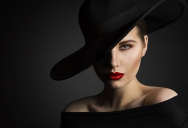 Elegant Woman Face Portrait hidden by Black Hat. Beauty Fashion Model with Red Lips and Eye Make up over dark Gray Background clipart