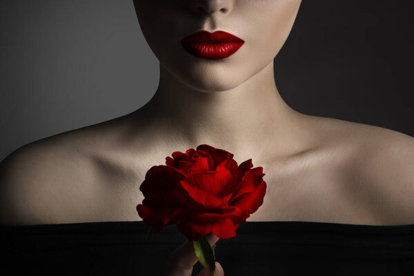 Red Rose Flower and Model Lips Close up Fine Art Portrait. Beauty Model Face and Shoulders Make up. Elegant Mysterious Lady over Black